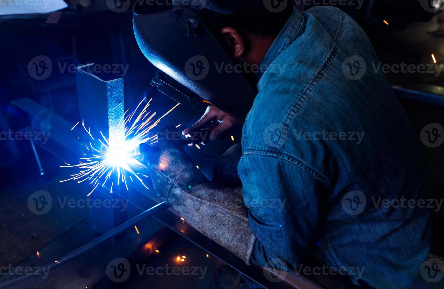 soldador de soldadura de metal con máquina de soldadura por arco de argón y tiene chispas de soldadura. un hombre usa máscara de soldadura y guantes protectores. seguridad en el lugar de trabajo industrial. soldador trabajando con seguridad. industria metalúrgica. foto