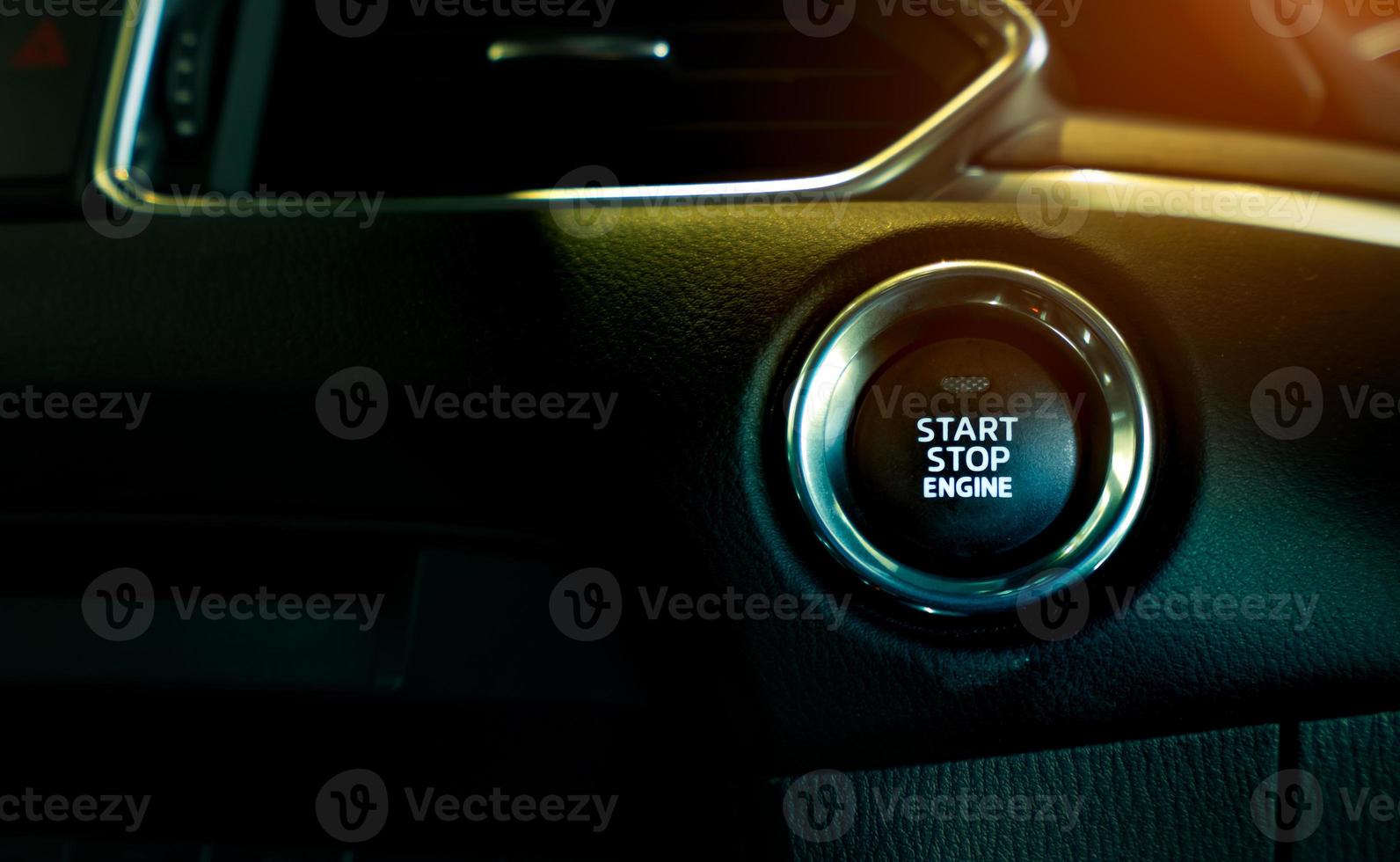 Start stop engine button of luxury car. Push up button for start or stop car engine in keyless automobile. Turn key with ignition system concept. Black ignition switch. Car dashboard interior view. photo