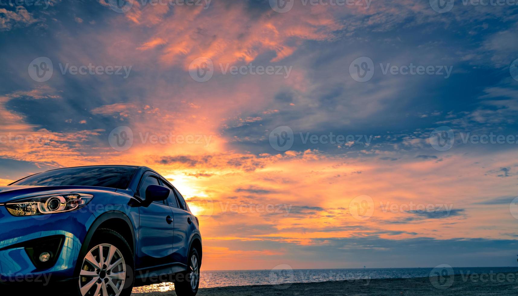 coche suv compacto azul con diseño deportivo y moderno estacionado en la playa al atardecer. tecnología de coches híbridos y eléctricos. plaza de aparcamiento. industria automotriz. antecedentes comerciales de cuidado de automóviles. cielo hermoso. foto