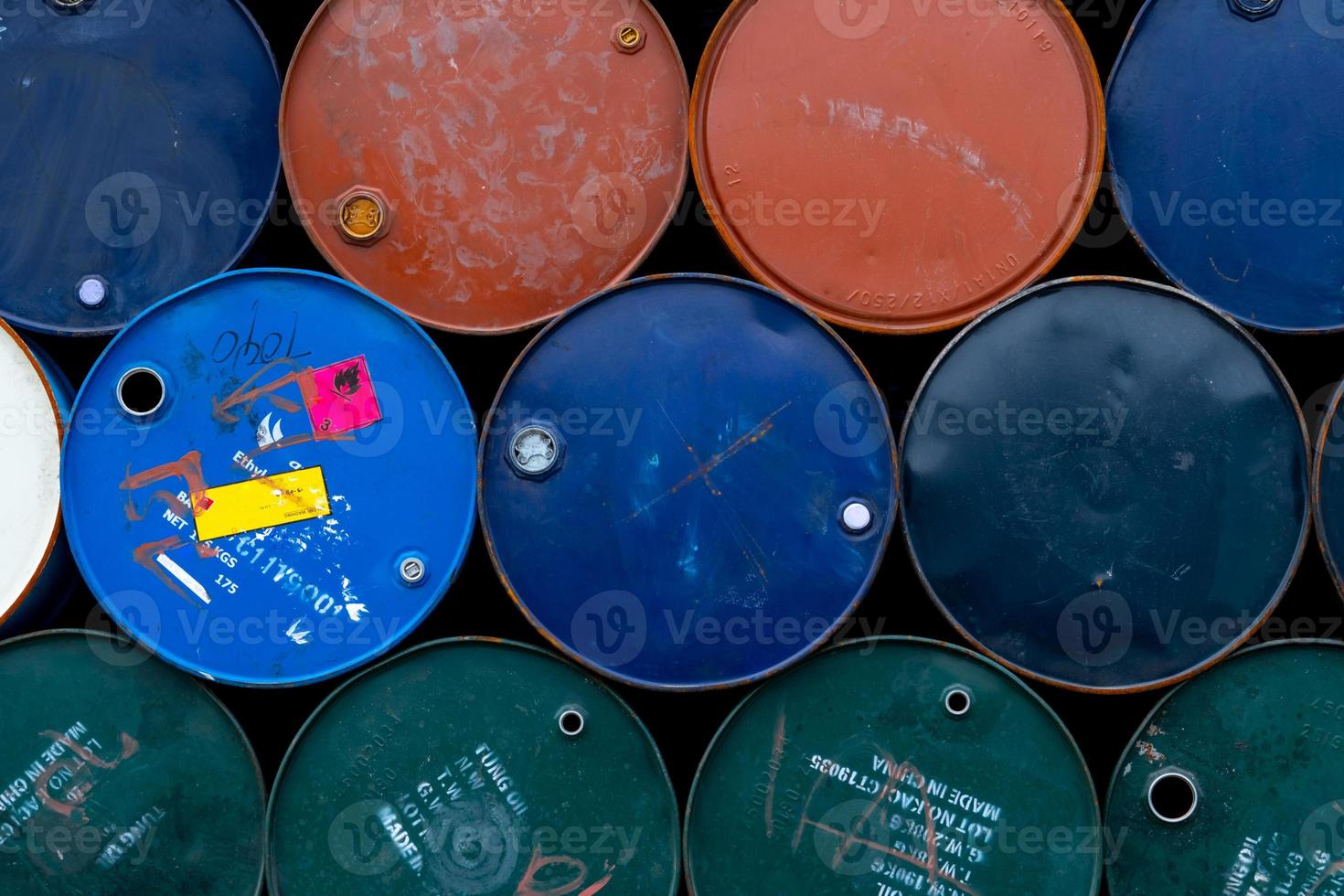 Old chemical barrels. Blue, green, orange oil drum. Steel oil tank. Toxic waste warehouse. Hazard chemical barrel with warning label. Industrial waste in metal drum. Hazard waste storage in factory. photo