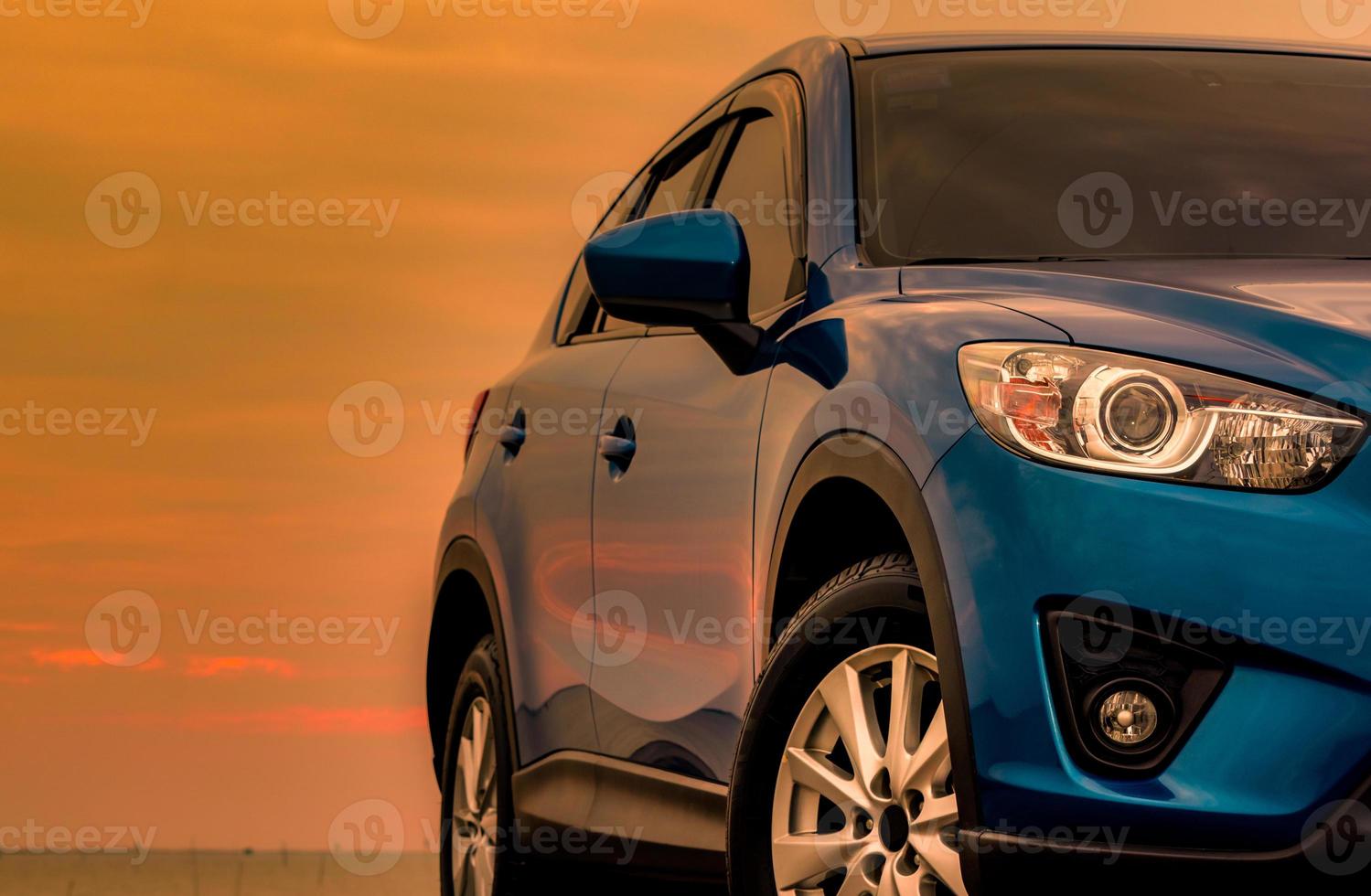 Blue compact SUV car with sport and modern design parked on concrete road by the sea at sunset in the evening. Hybrid and electric car technology concept. Car parking space. Automotive industry. photo