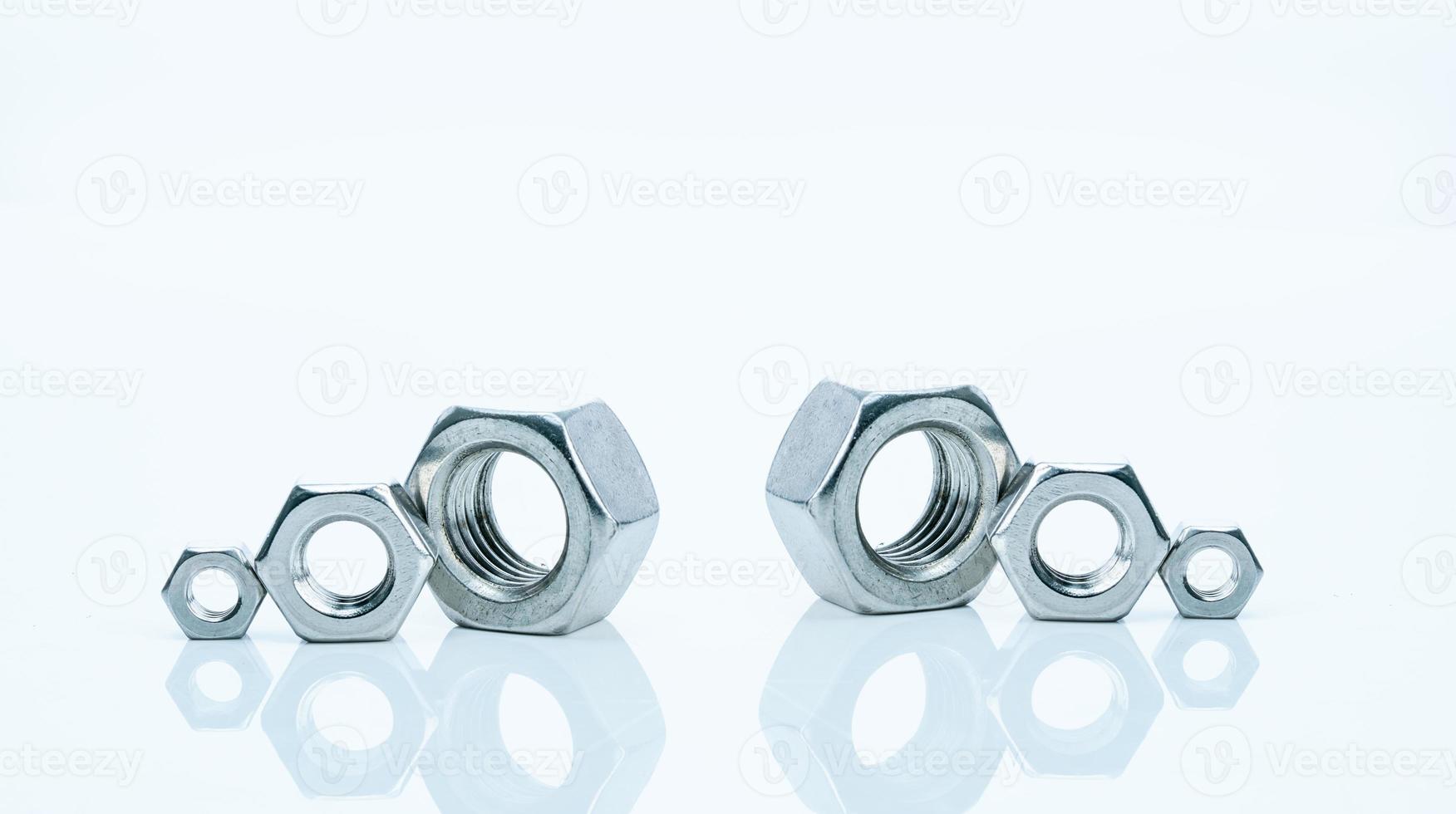 Set of metal hexagon nuts isolated on white background. Small, medium, and big of silver metal hexagon nuts. Hardware tool. Fastener with a threaded hole. Pattern of six metal nuts with copy space. photo