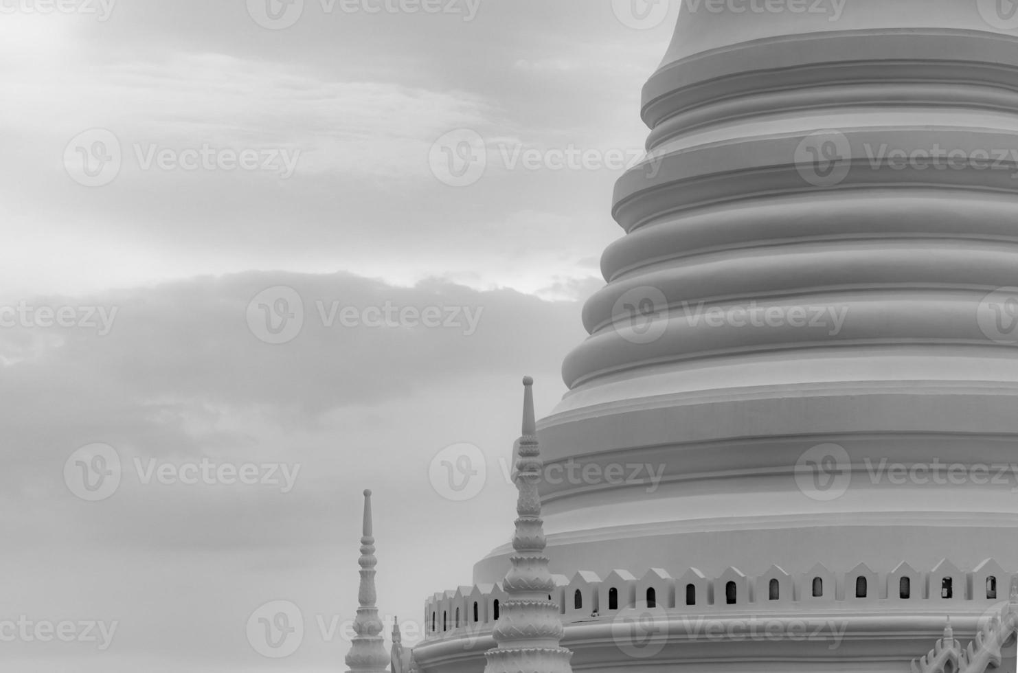 Closeup white pagoda in Thai temple. Classical architecture. Attraction art and ancient architecture in Thailand. Buddhist temple with white sky and gray cloud. Religion architecture. Peaceful concept photo