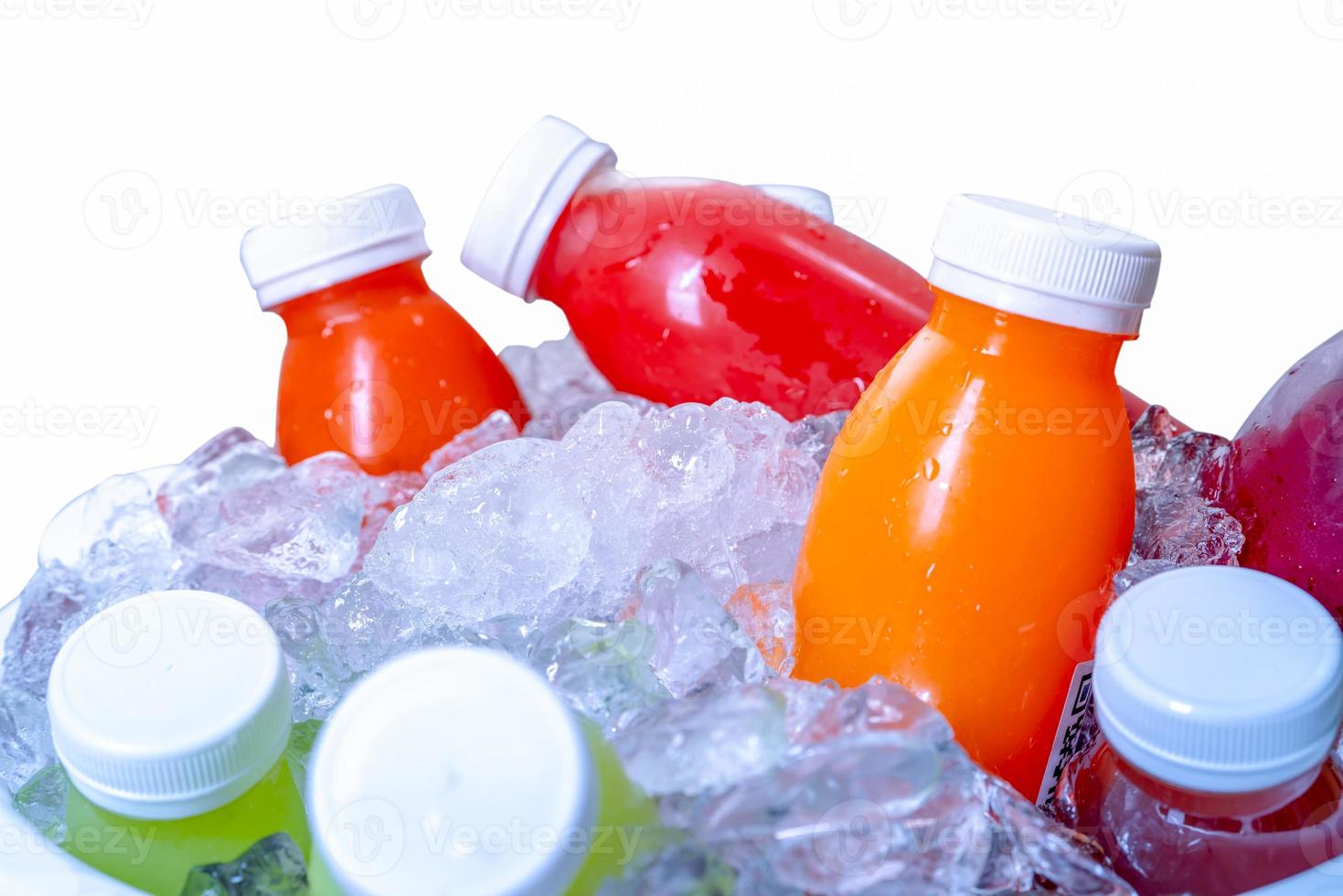 Organic cold pressed raw vegetable and fruit juice bottle in crushed ice bucket on white background. Healthy drink. Trendy juice beverage. Detox juice from fresh fruits and vegetables. Orange juice. photo