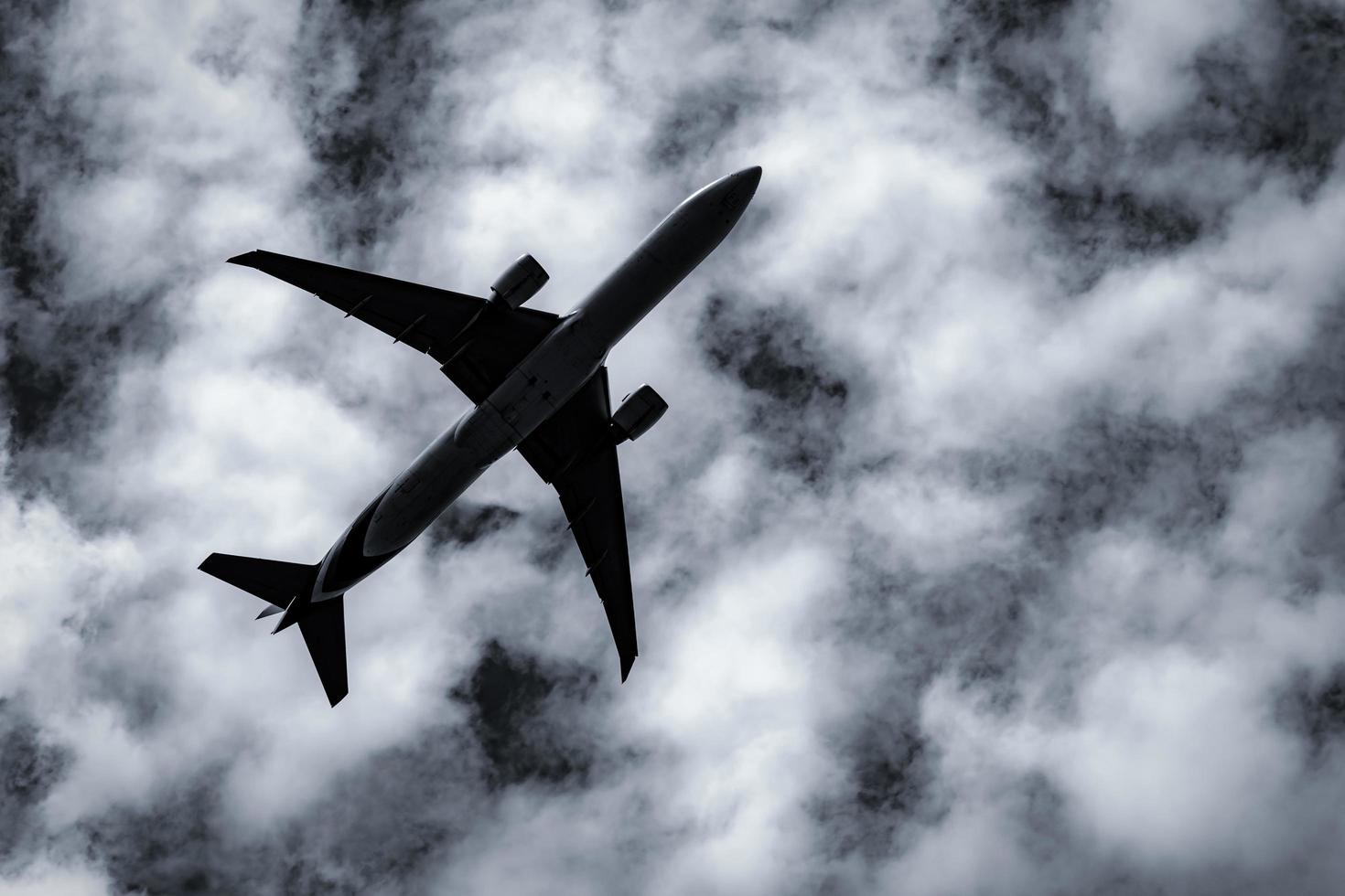 Commercial airline flying on dark sky and white fluffy clouds. Under view of airplane flying. Aviation business crisis from coronavirus. Failed journey vacation flight. Air transportation. Sad travel. photo