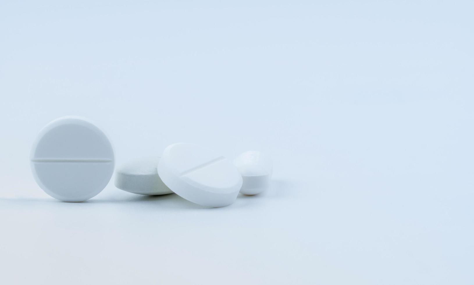 Pile of white round tablet pills isolated on white background. Selective focus on white tablet pills. Pharmaceutical industry. Pharmacy or drugstore symbol. Global healthcare. Health and pharmacology. photo