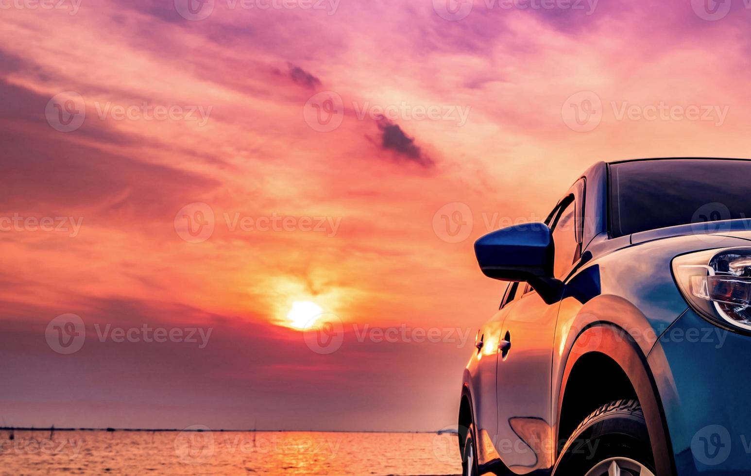 camión suv compacto azul con diseño deportivo y moderno estacionado en una carretera de hormigón junto al mar al atardecer. tecnología respetuosa con el medio ambiente. concepto de éxito empresarial. foto