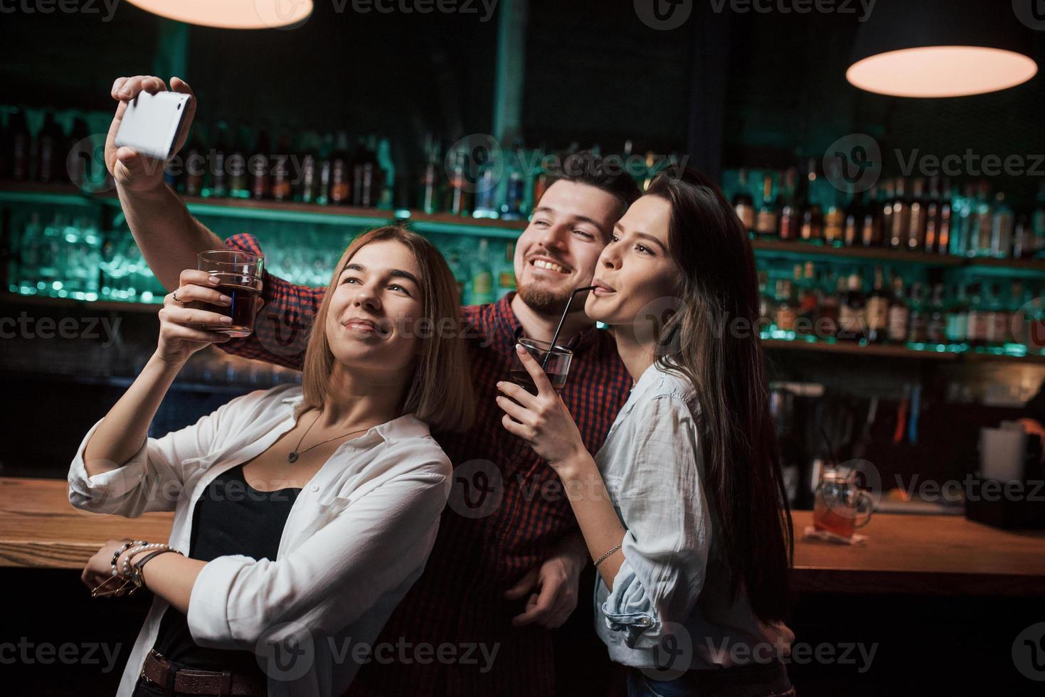 Near the bar with alcohol. Friends taking selfie in beautiful