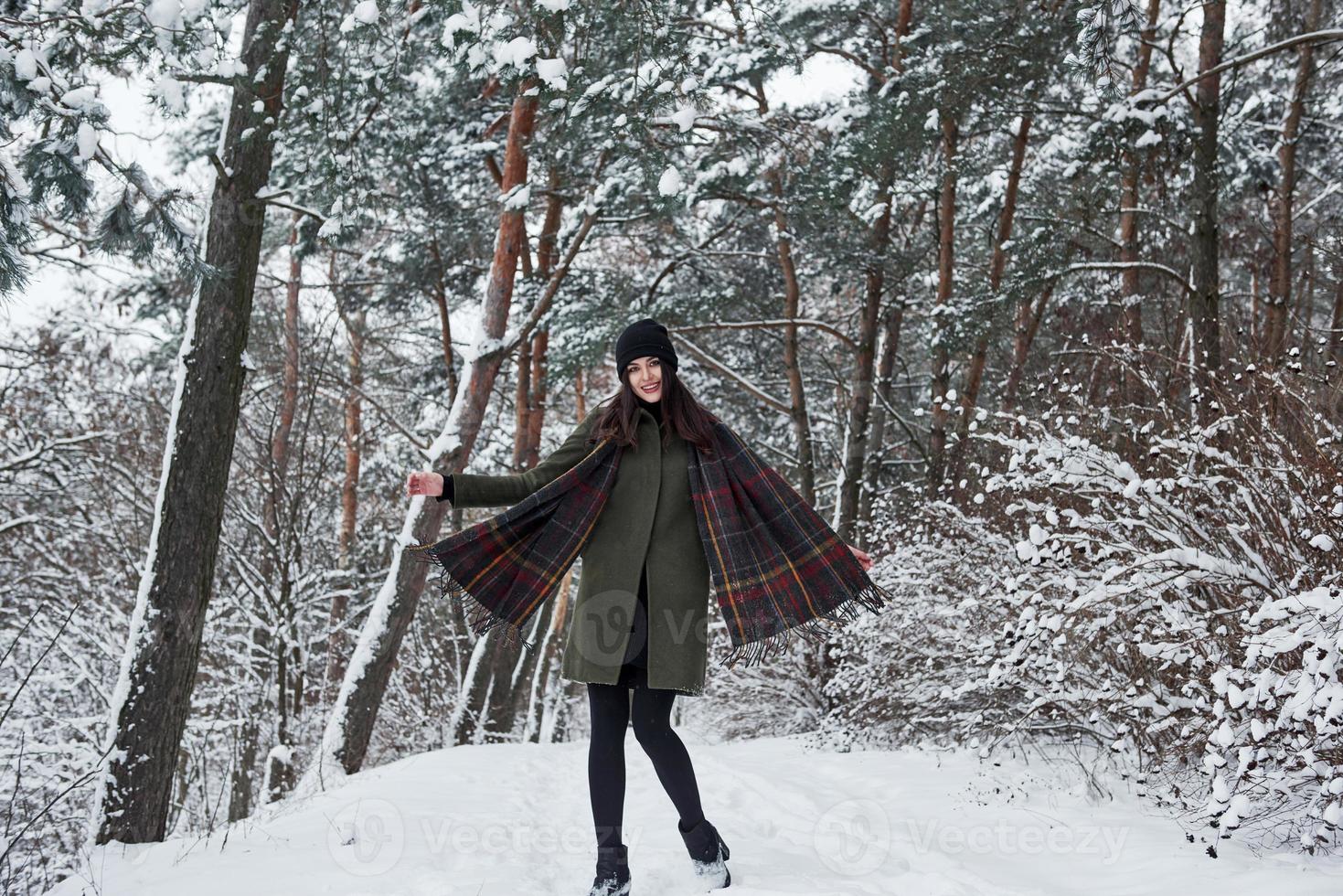 bien vestido para esa temporada. una joven alegre con ropa de abrigo da un paseo por el bosque de invierno durante el día foto