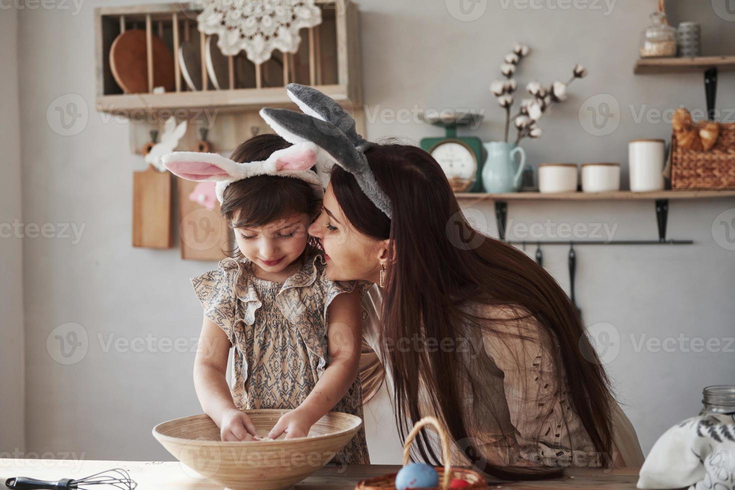 Family bonding. Mother and daughter in bunny ears at easter time have some fun in the kitchen at daytime photo