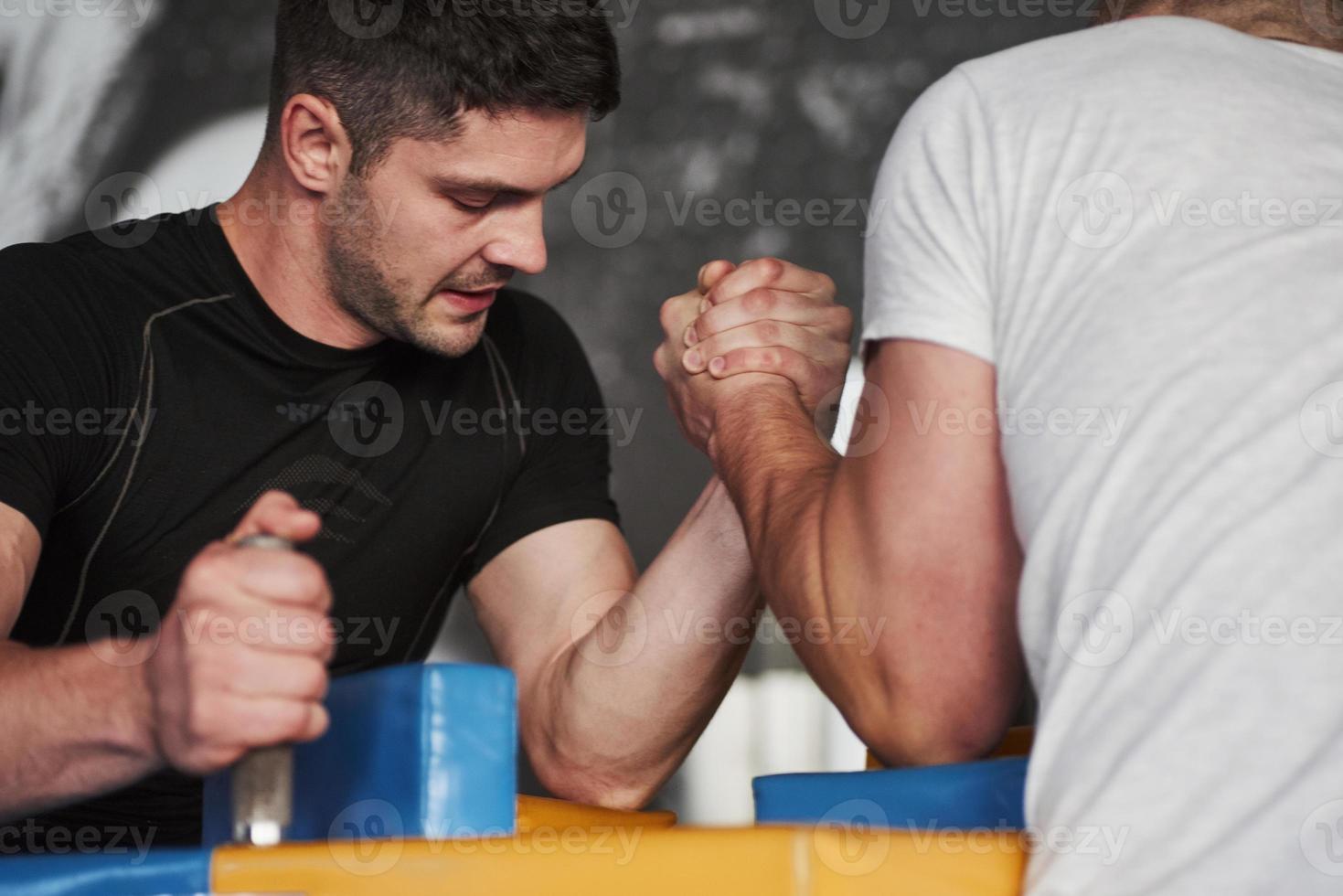 Struggling for win. Arm wrestling challenge between two men. Match on a special table photo