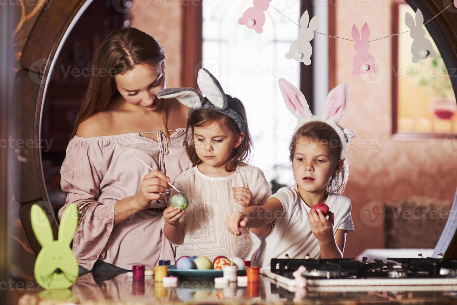 lindos miembros de la familia. que tengas felices pascuas. dos niñas aprendiendo a pintar huevos para las fiestas foto