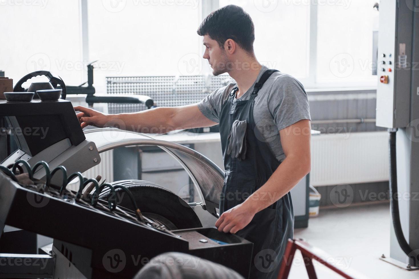 Programming the device. Young man works with wheel's disks at the workshop at daytime photo