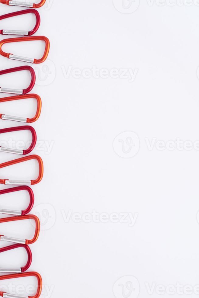 Huge choice. Many of the red colored carabiners on lying on the white table photo