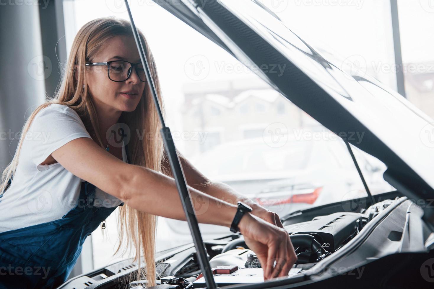 reemplazo de una pieza. en el hermoso trabajo. mujer adicta al coche repara automóvil negro en el interior foto