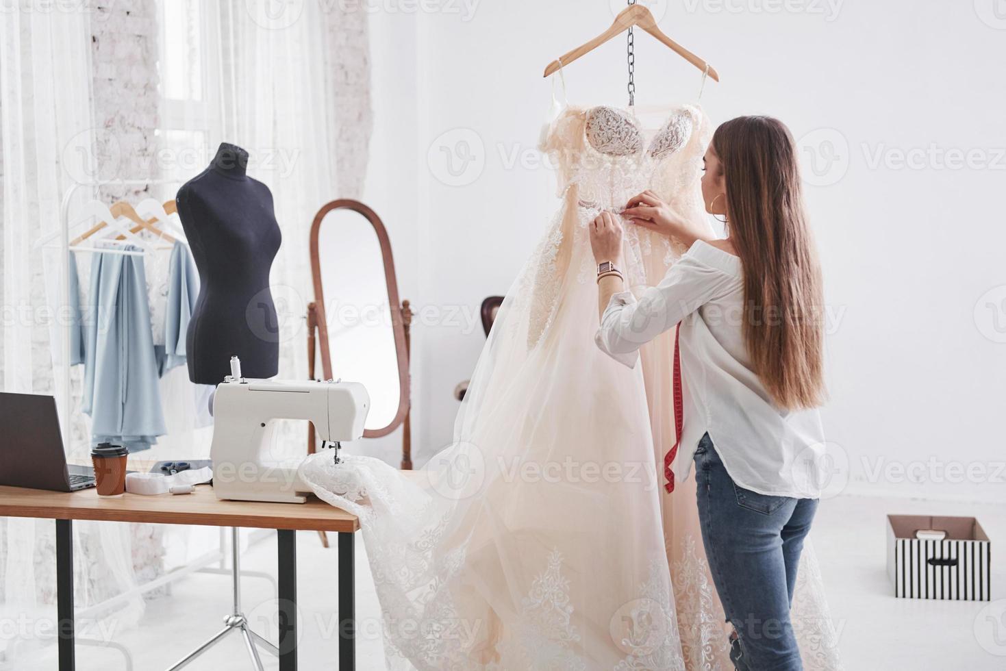 algunas medidas. diseñadora de moda femenina trabaja en la ropa nueva en el taller foto