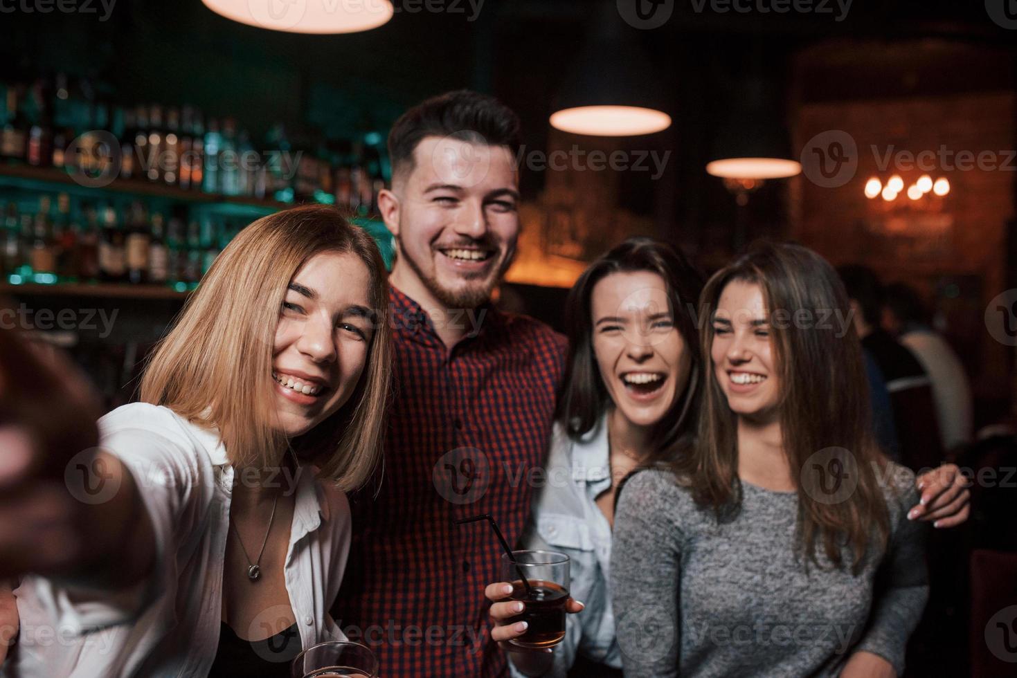 Imitation of photo from the phone. Friends taking selfie in beautiful nightclub. With drinks in the hands