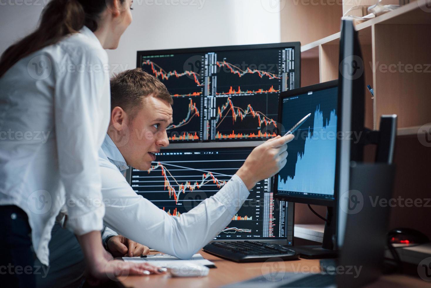 High and nice results. Team of stockbrokers are having a conversation in a office with multiple display screens photo