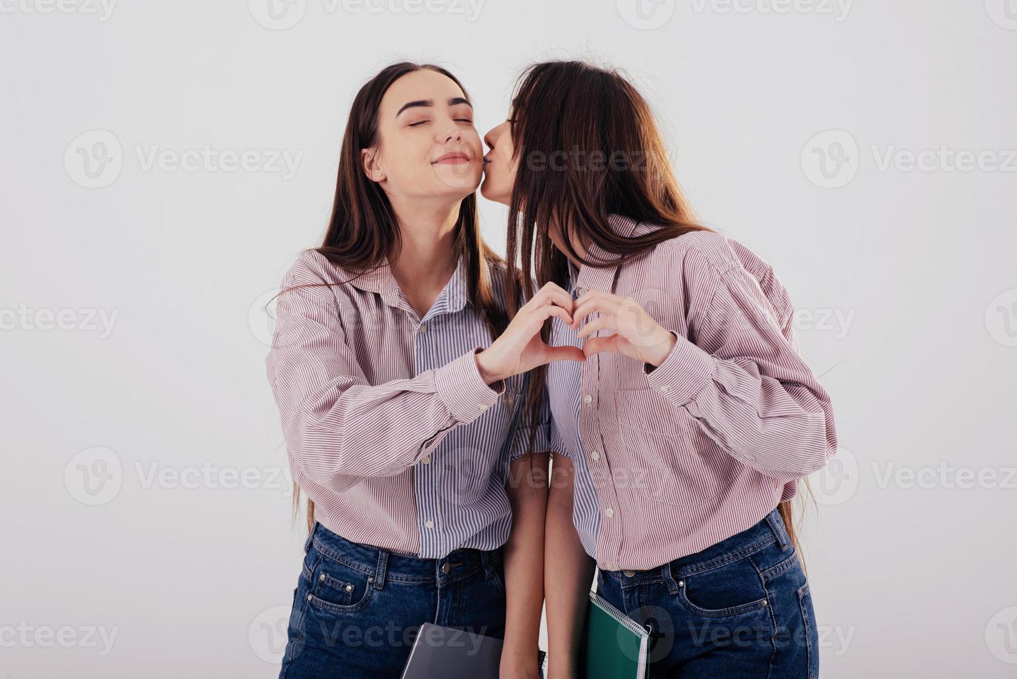 Family ties. Girl gives kiss. Two sisters twins standing and ...