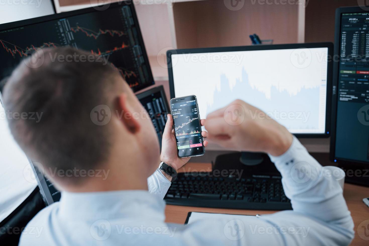 Man working online in the office with multiple computer screens in index charts photo