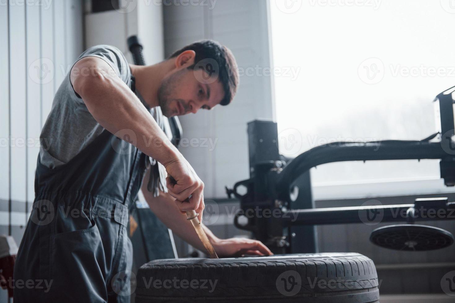 Easy part. Young man works with wheel's disks at the workshop at daytime photo