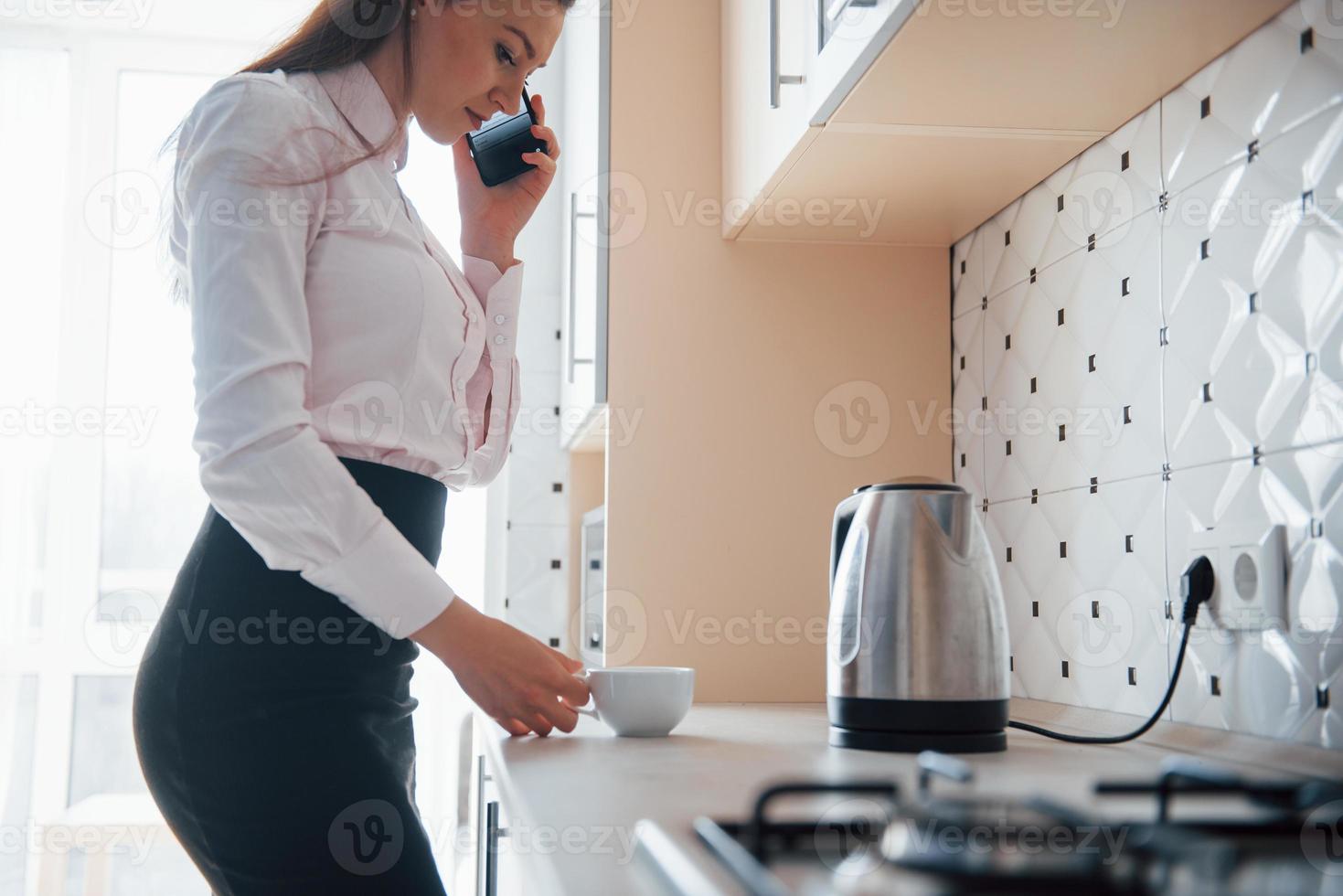 Morning of busy person. Young businesswoman with black hair in official clothes at her home photo
