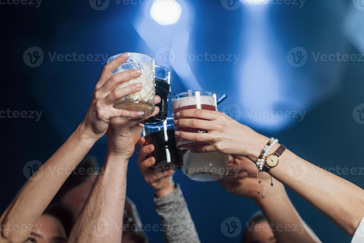 Variety of drinks. Group of young friends smiling and making a toast in the nightclub photo