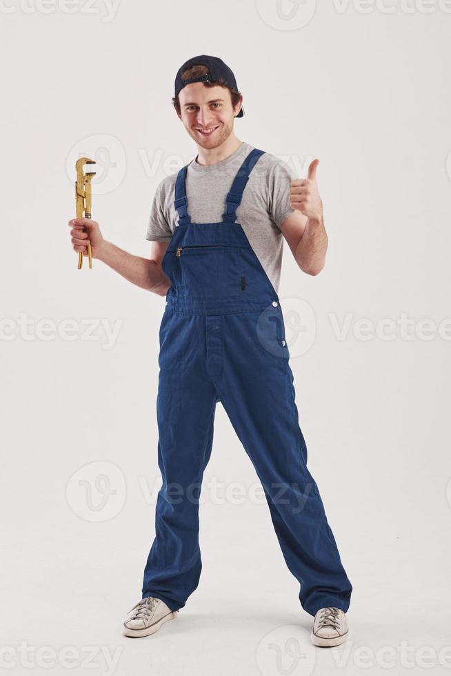 Happy worker. Man in blue uniform stands against white background in the studio photo