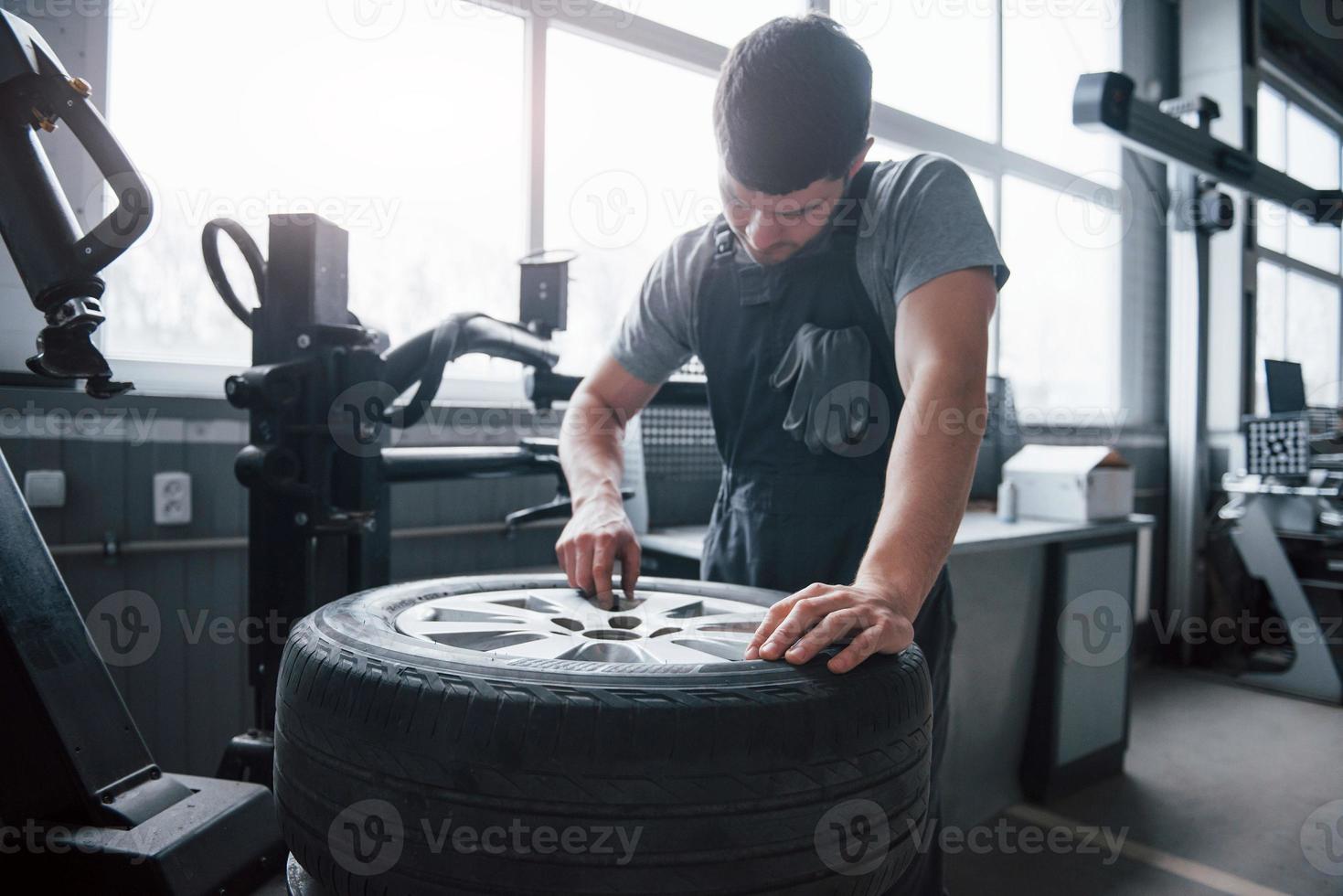 Careful with that. Young man works with wheel's disks at the workshop at daytime photo