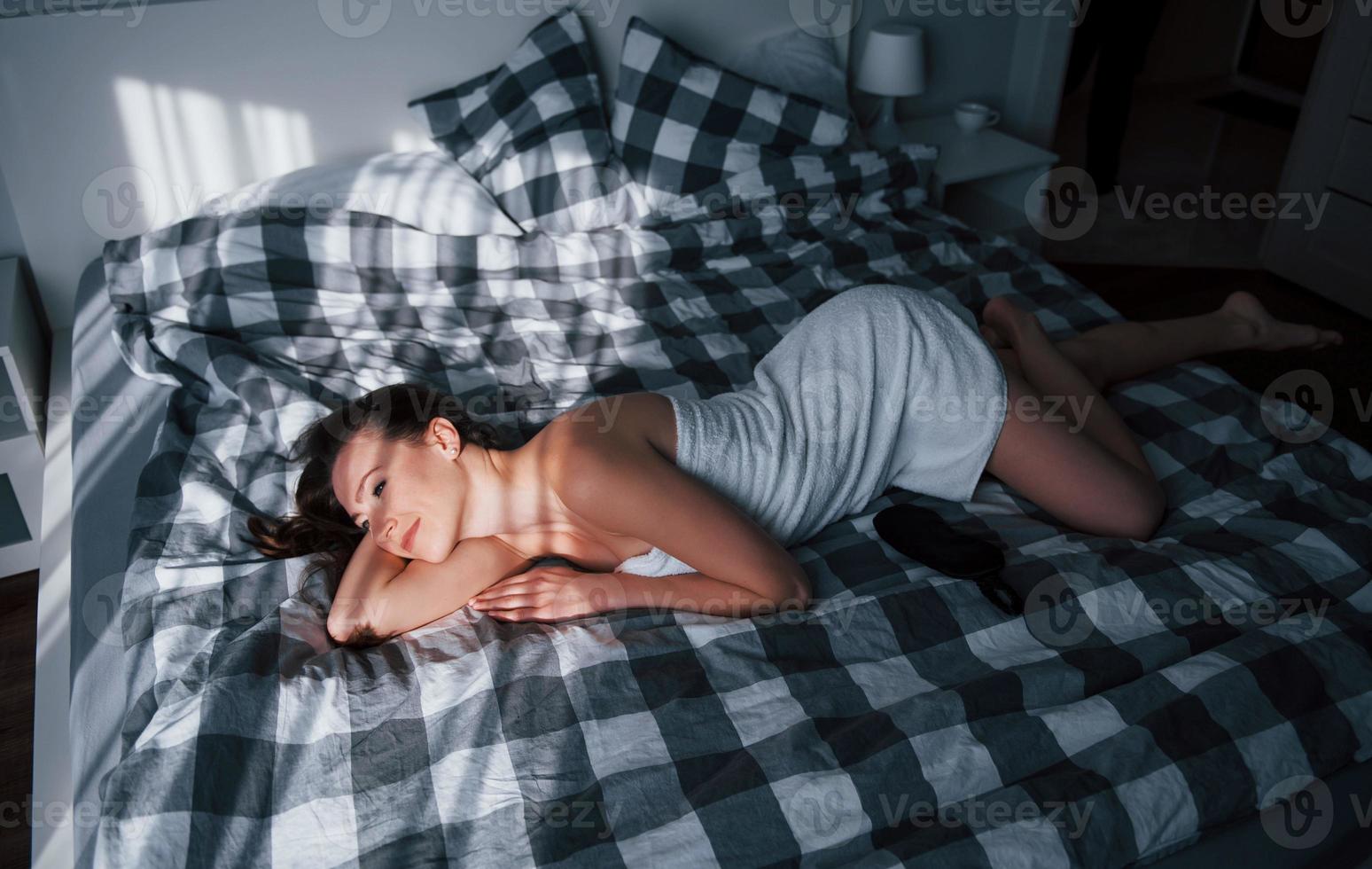 Resting and feeling good. Pretty young woman lying on the bed at morning time in her room photo