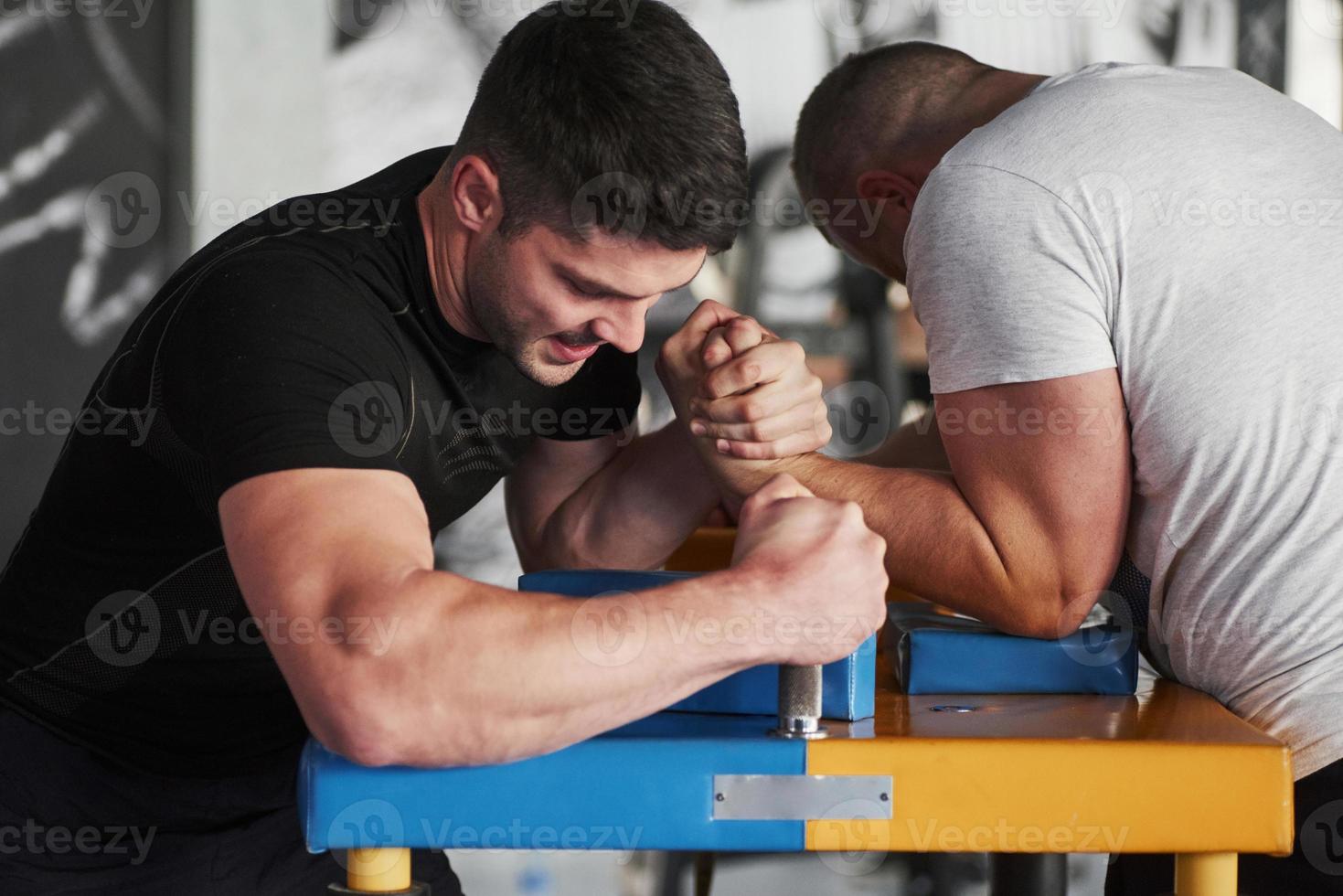 People is struggling to win. Arm wrestling challenge between two men. Match on a special table photo