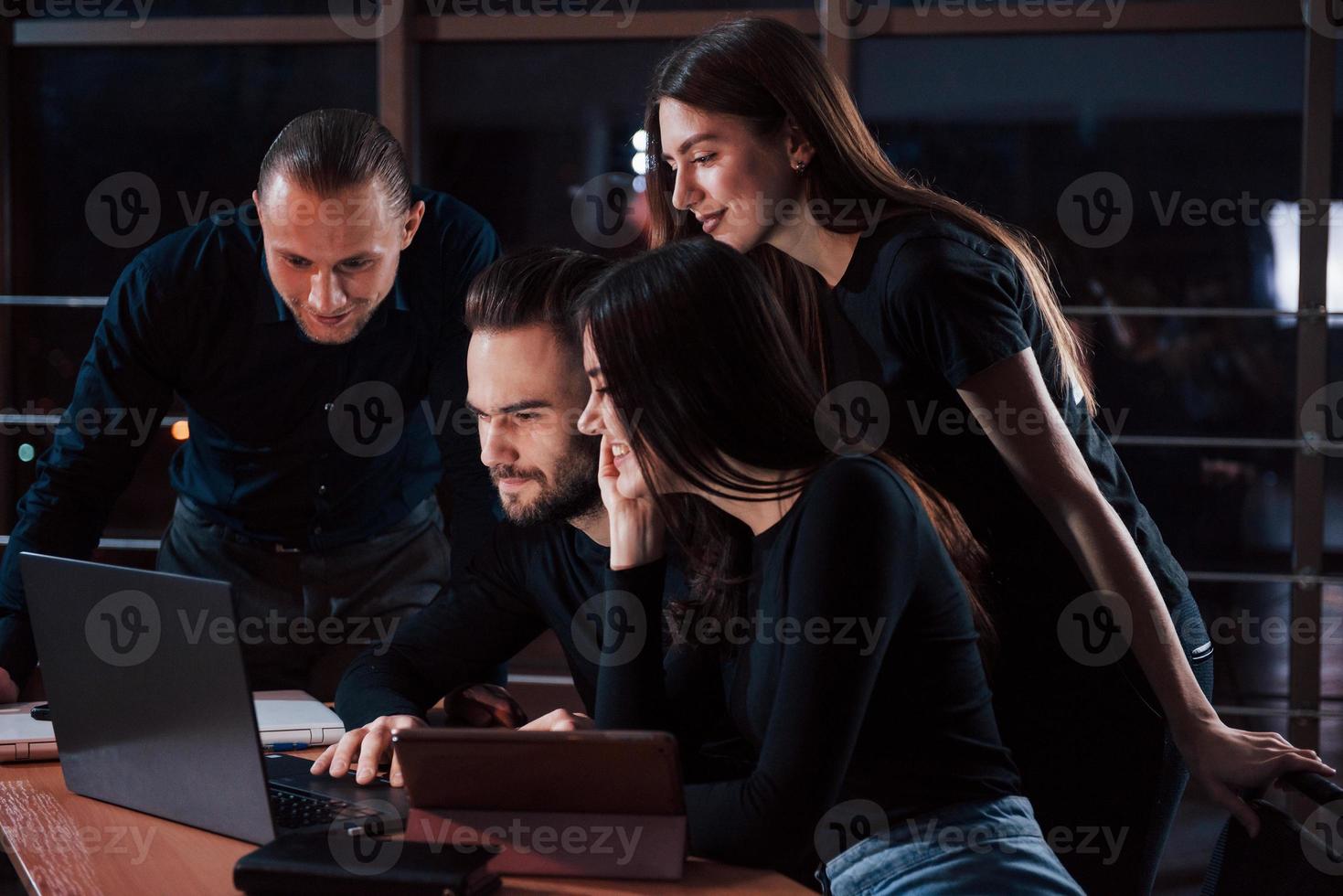 Modern business. Team of young people works on their project at night time in the office photo