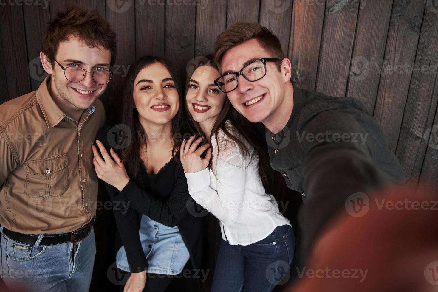 todos están sonriendo. tomando autofoto. cerrar la vista frontal de los amigos. hombre con gafas de sol en la habitación foto