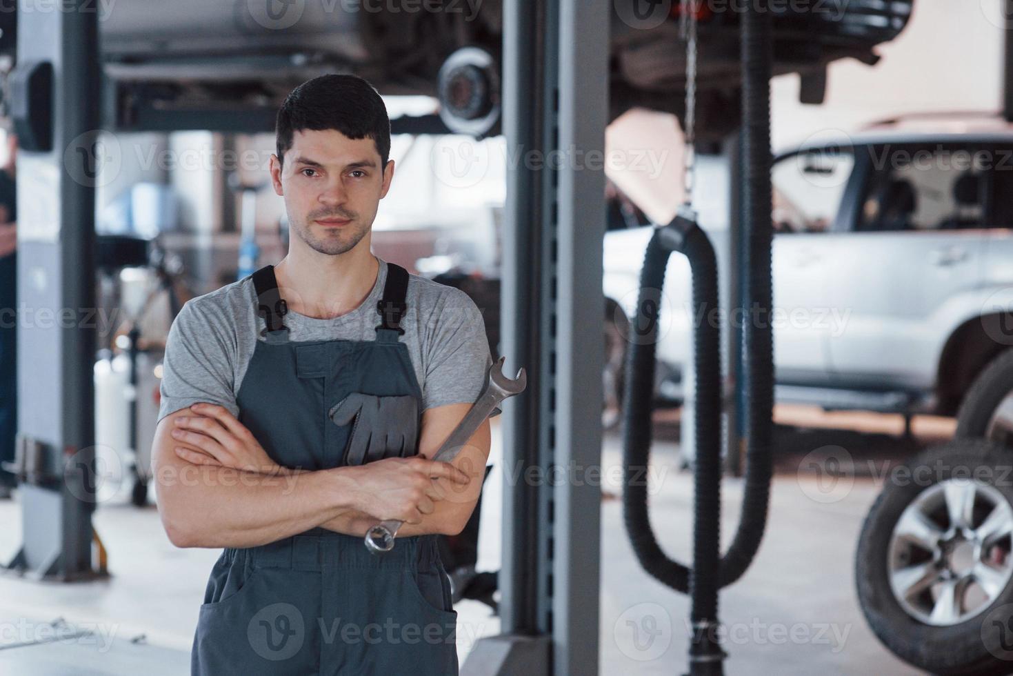 One person in the room. Portrait of serious worker in uniform that stands in his workshop with wrench in hand photo