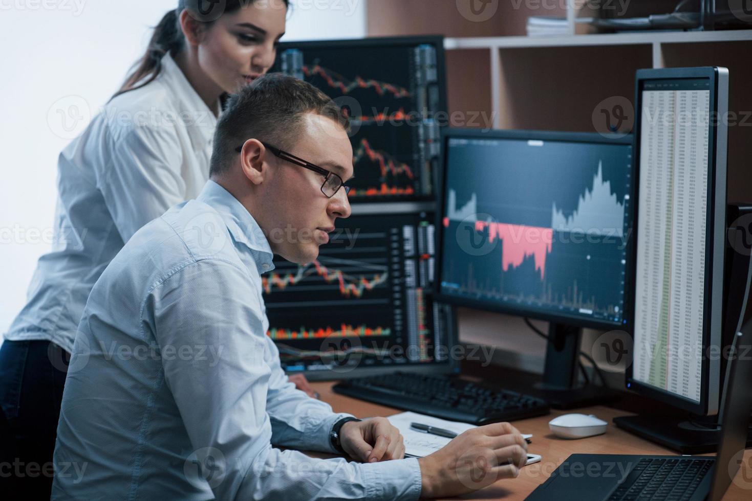 Making smart decisions. Team of stockbrokers are having a conversation in a office with multiple display screens photo