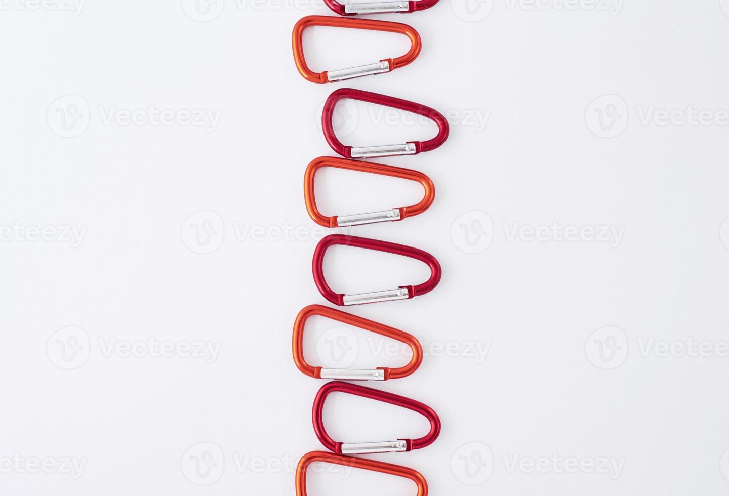 In the center of image. Many of the red colored carabiners on lying on the white table photo