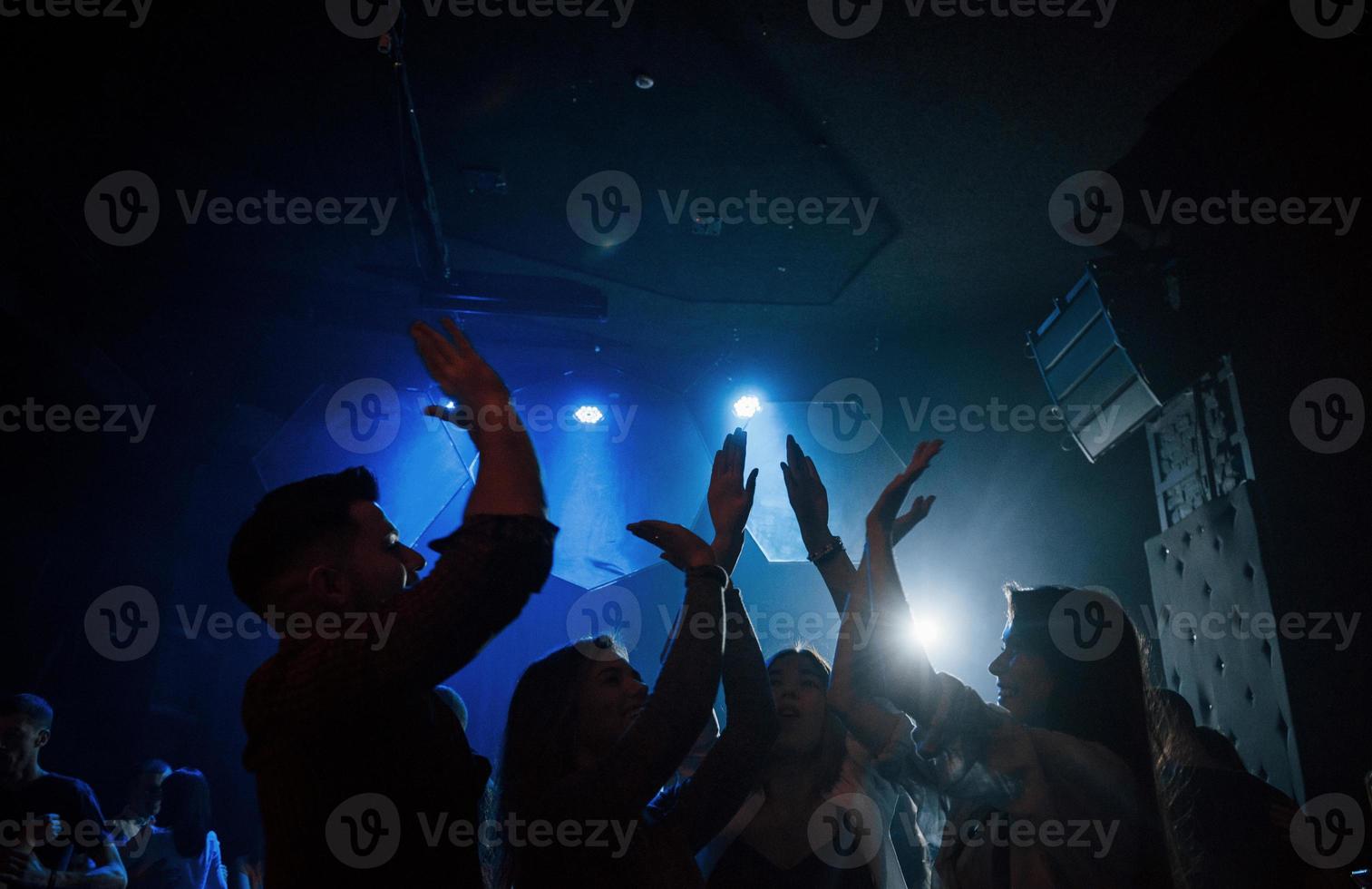 We are awesome. Group of people that enjoying dancing in the nightclub with beautiful lightings photo