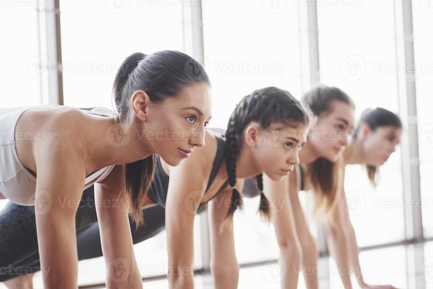 vista lateral. Grupo de chicas deportivas en un amplio gimnasio con grandes ventanales tienen entrenamiento. foto