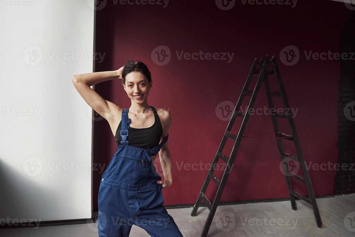 posando para la cámara. joven ama de casa decidió pegar papel tapiz en su nueva casa en la habitación foto