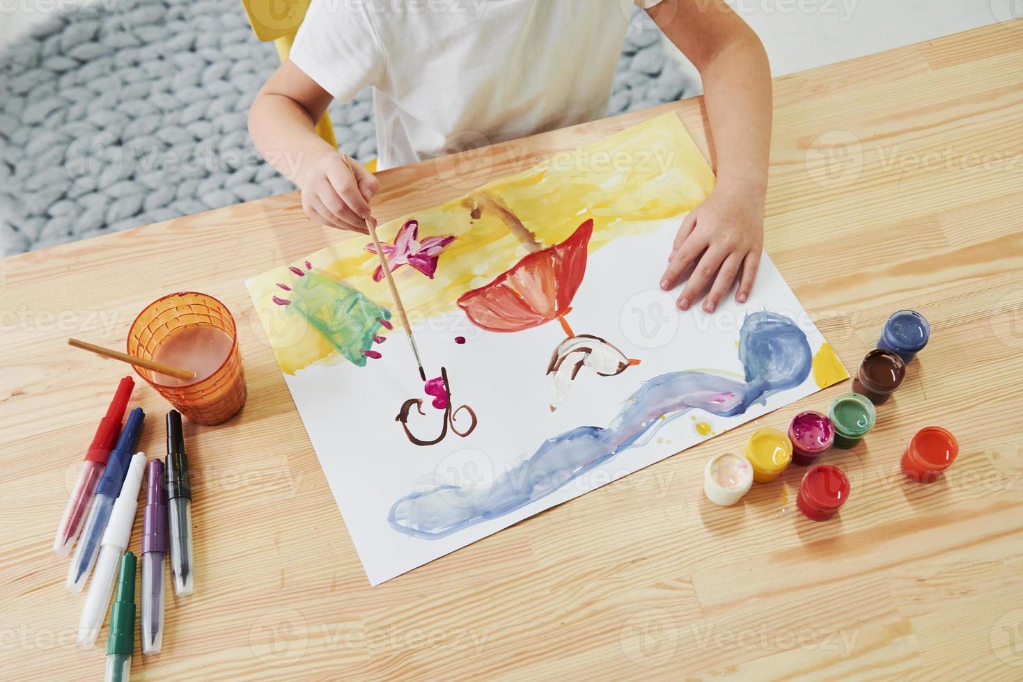 Just a few moments and picture will be done. Little girl is drawing by using gouache and brush. Learning in the art class photo