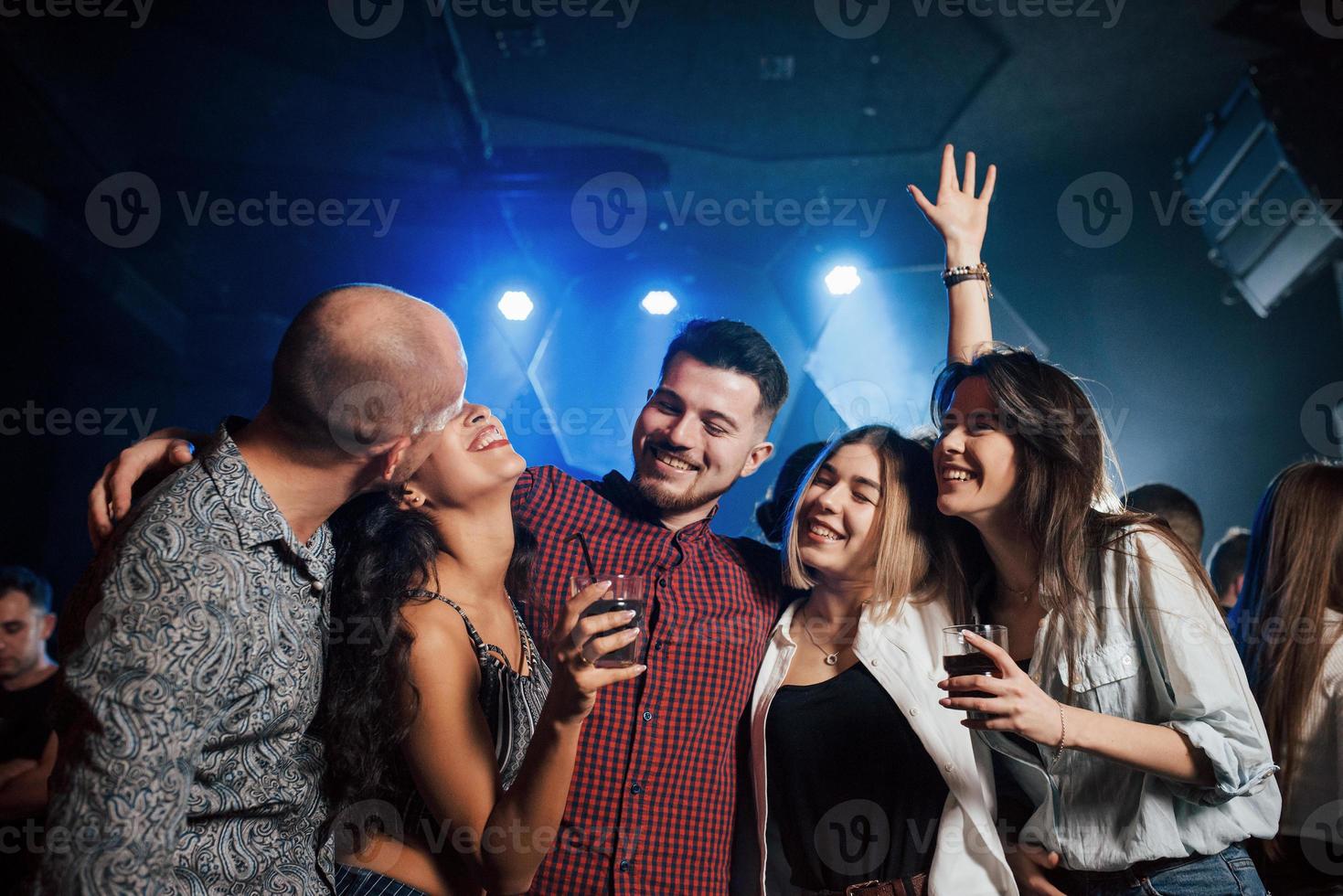 Bald guy kisses his wife. Beautiful youth have party together with alcohol in the nightclub photo