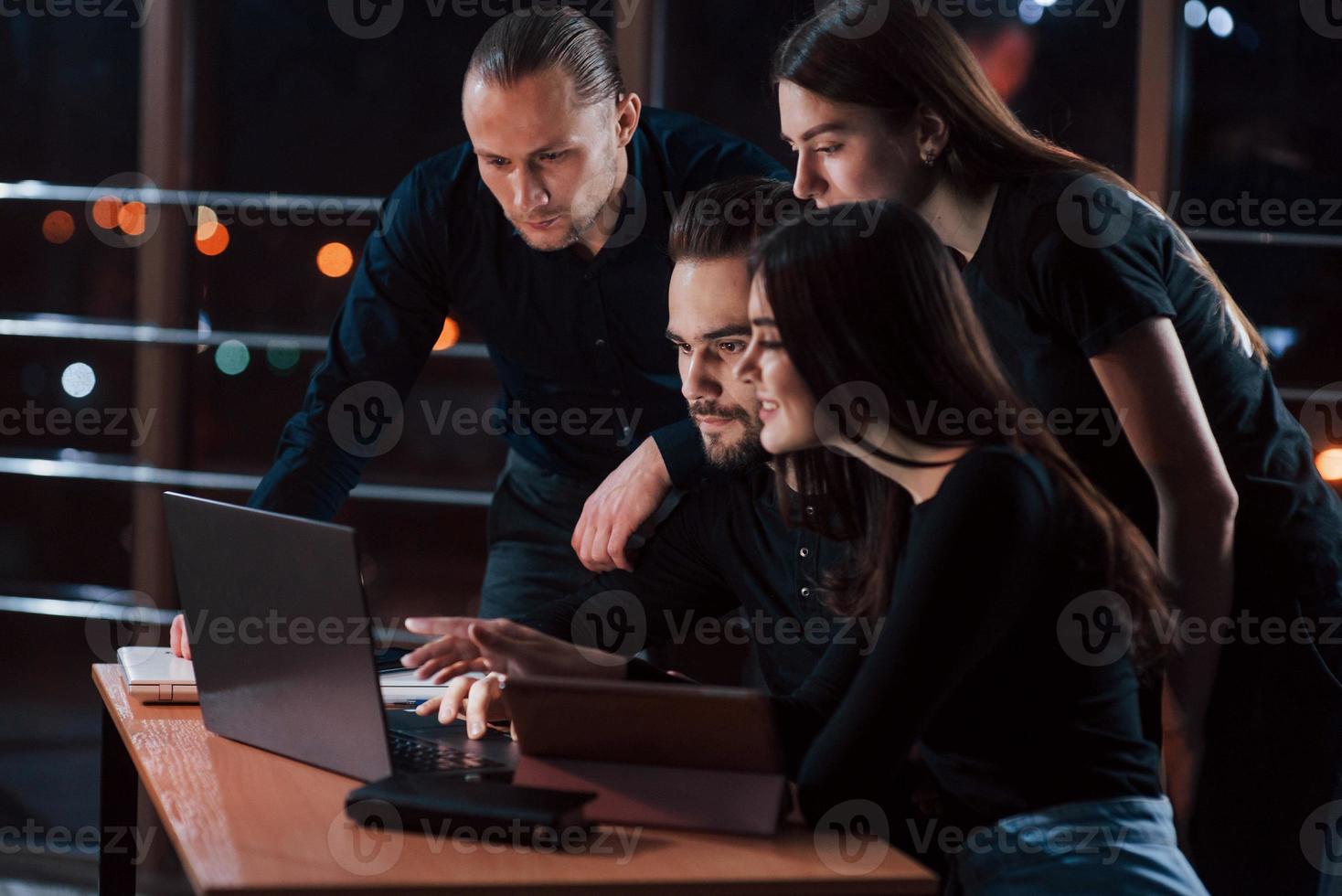 I definitely like the results. Team of young business people works on their project at night time in the office photo