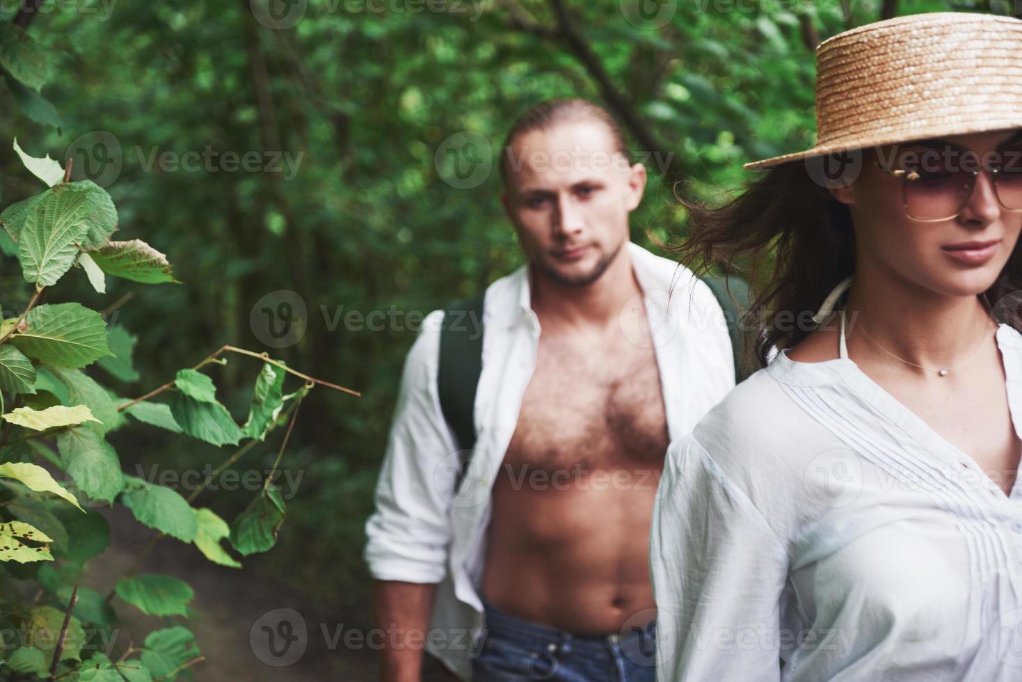 Two hikers with backpacks on the back in nature. Young couple man and woman like an active holiday with a tent, so they got out on the nature in a sunny day photo