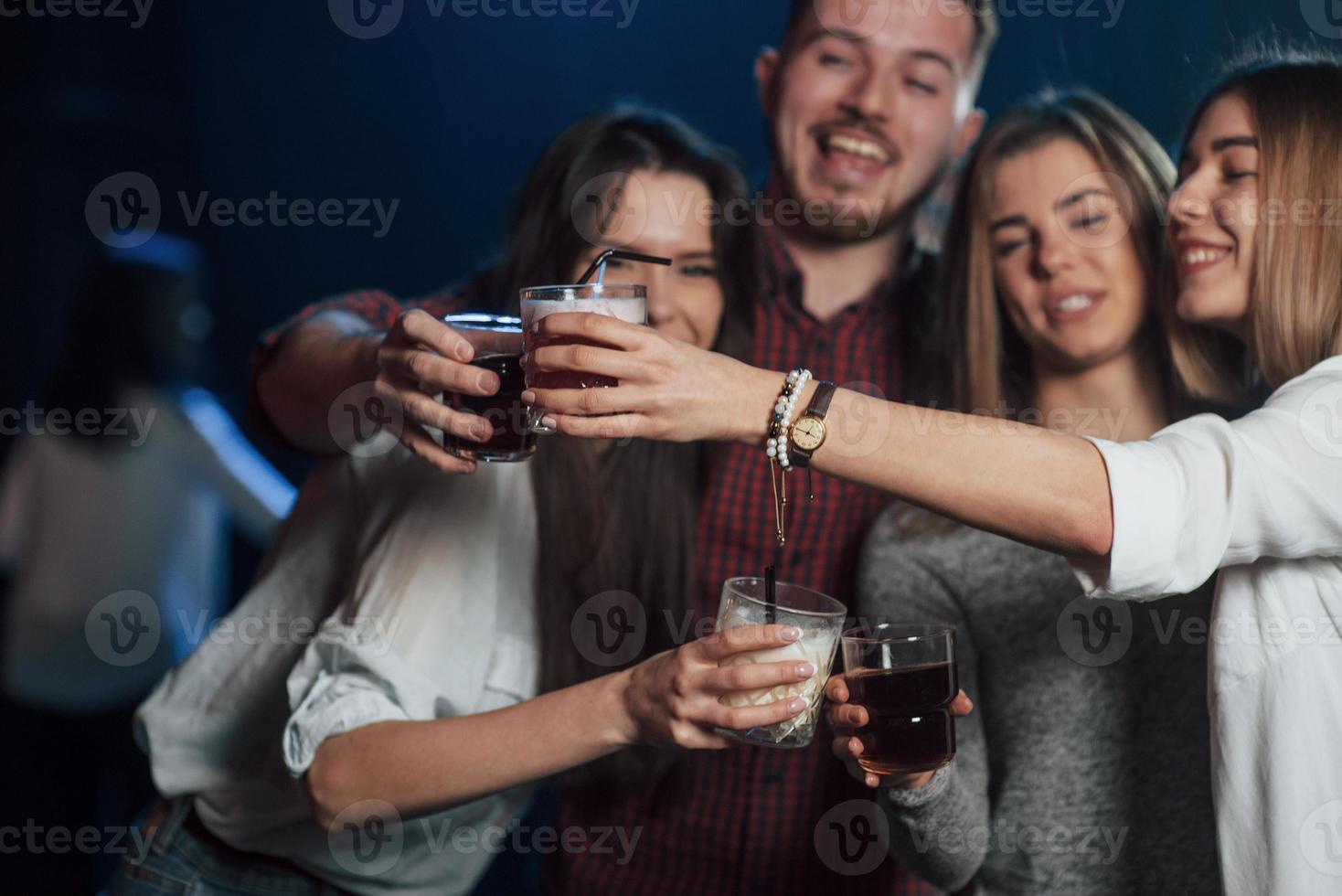 That's is what they call a party. Group of young friends smiling and making a toast in the nightclub photo