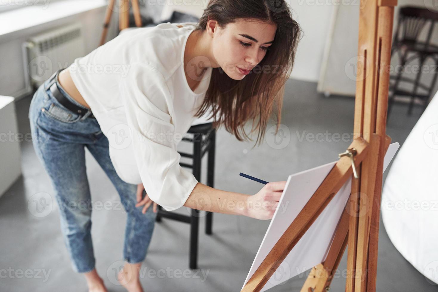 That's how drawings are make. Young brunette in the room with white walls and daylight that comes from the window photo