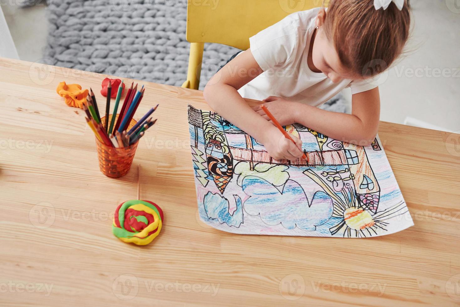 In process. Cute little girl in art school draws her first paintings by pencils and markers photo