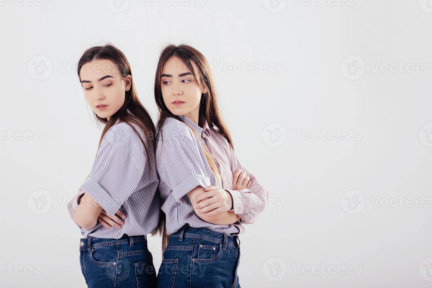 concepción de dos familiares ofendidos. dos hermanas gemelas de pie y posando en el estudio con fondo blanco foto