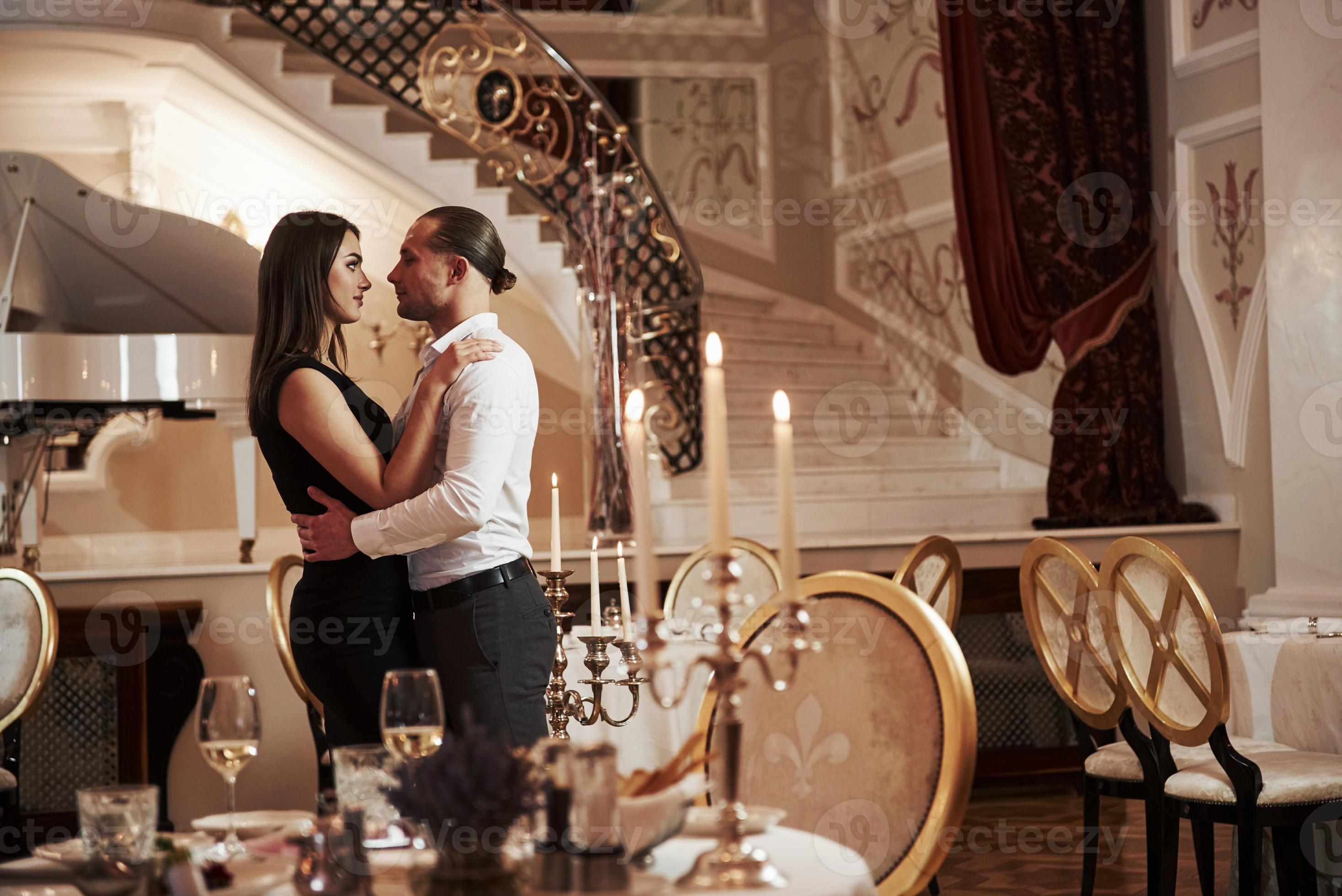 Guy going to kiss his woman. Beautiful couple have romantic dinner in luxury restaurant at