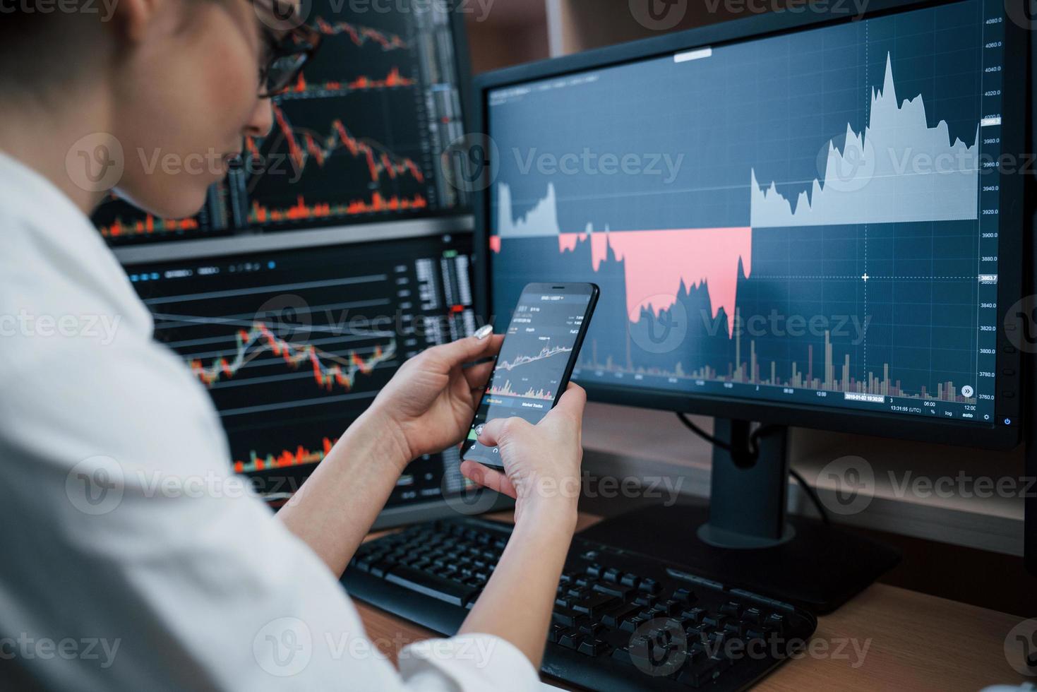 Ordinary day. Woman working online in the office with multiple computer screens in index charts photo