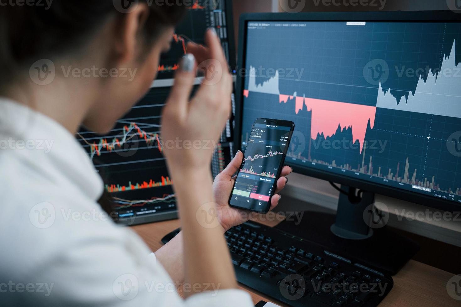Entrepreneur looks at the project information. Woman working online in the office with multiple computer screens in index charts photo